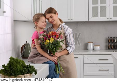 Little Daughter Congratulating Mom With Bouquet Of Flowers In Kitchen. Happy Mother's Day