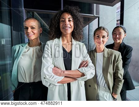 Four Multiracial Empowered Women Looking At Camera Confident And Cheerfully At The Office.