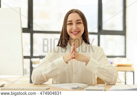 Female Office Worker Smiles Happily. Woman Rejoices At Successful Development Of Affairs Sitting At 