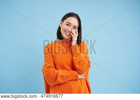 Portrait Of Young Happy Woman In Orange Jamper, Touches Her Clear Glowing Skin, Has Beautiful White 