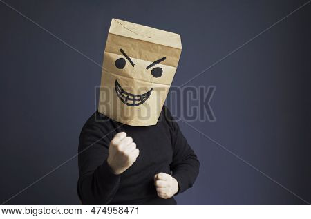 A Man In A Black Turtleneck With A Bag On His Head, With A Drawn Angry Emoticon, Shows His Fist Whil