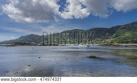 Low Tide On The Beach Of A Tropical Island. The Boat Is Moored In Shallow Water. Ripples On The Shin