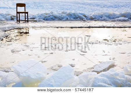 Icebound Chair Near Ice Hole In Frozen Lake