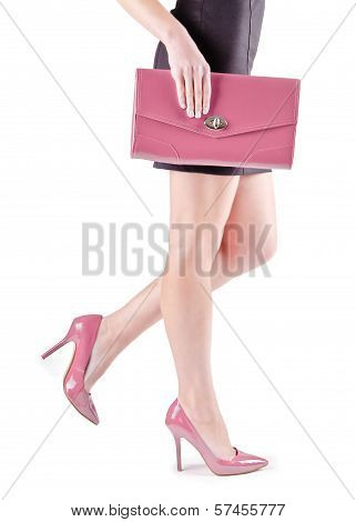 Slender beautiful female feet in pink shoes and mini bag