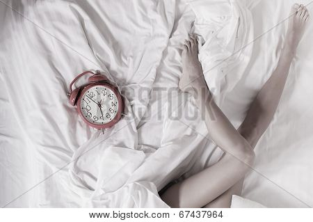 Sexy Female Legs With Clock On Bed In Bedroom