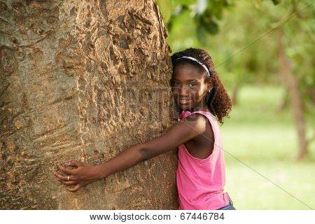 Portrait Of Black Ecologist Girl Hugging Tree And Smiling