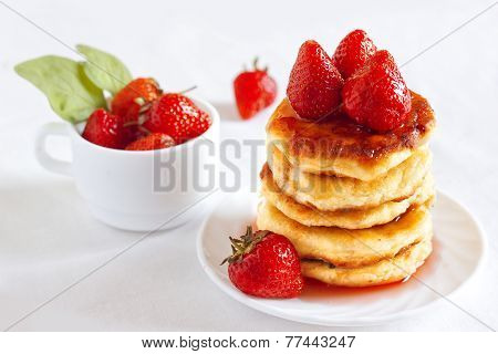 Delicious homemade cheese pancakes with strawberry poured with jam