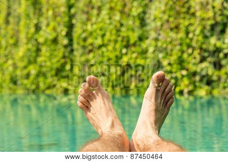 leisure, people, travel and tourism concept - close up of male feet over resort swimming pool