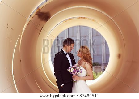 Bride And Groom Posing On Architectural Background