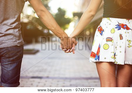 Young couple in love walking in the park holding hands looking in the sunset