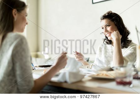 Two Beautiful Ladies Eating In A Restaurant While Having A Conversation