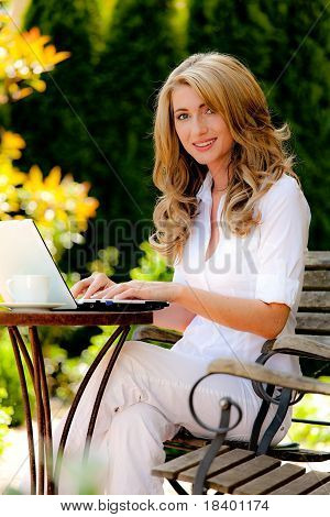 Frau mit Laptop im Garten