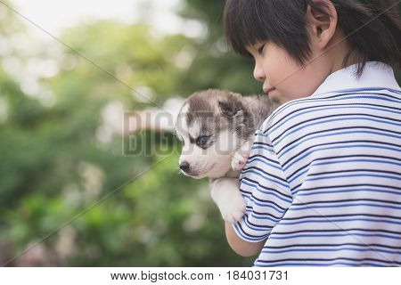 Cute asiaan child holding siberian husky outdoors