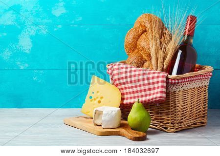 Basket with wine bottle bread and cheese on wooden table. Jewish holiday Shavuot concept.