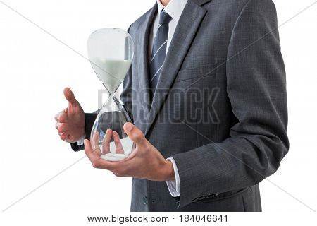 Mid section of businessman holding hourglass against white background