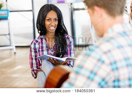 Students sitting on the floor with one playng guitar