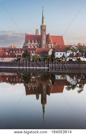 Wroclaw Poland 22nd october 2016. Church of the holy cross (St Bartholomew) on Ostrow Tumski (Cathedral Island) reflected in the Odra river at dawn.
