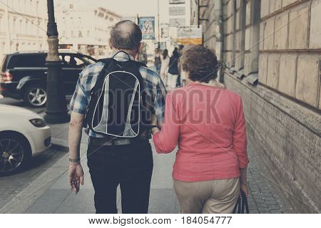 Back view of elderly couple walking in the city.