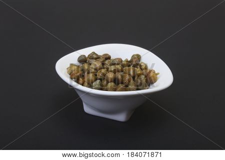 bowl with fresh capers isolated on black background.