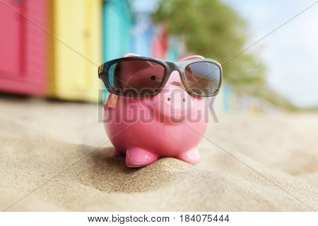 Piggy bank on sand beach vacation with sunglasses and bathing boxes