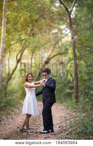 A couple in formal dress black suit and white dress romance dancing in the pine forest before wedding, Thailand