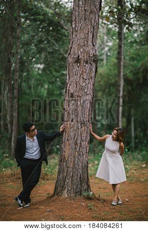 A couple in formal dress black suit and white dress romance in the pine forest before wedding, Thailand
