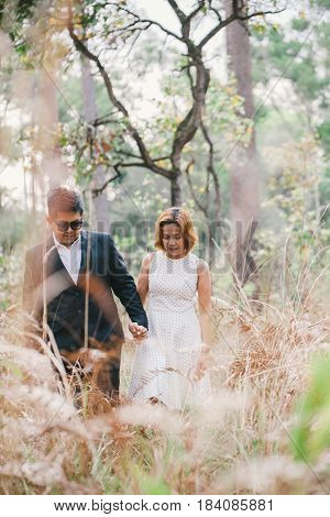 A couple in formal dress black suit and white dress romance in the pine forest before wedding, Thailand