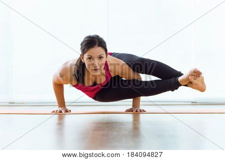 Portrait of beautiful young woman practicing acro yoga at home.