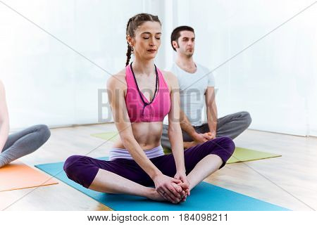 Portrait of beautiful young couple practicing yoga at home. Baddha Konasana pose.