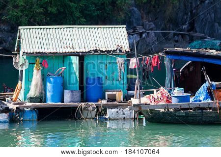 Floating fishing village with rock island in background, Ha Long bay, Vietnam.