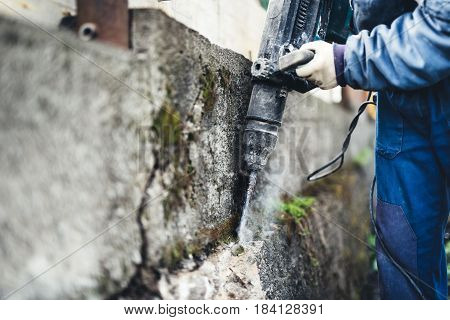 Worker Using Industrial Construction Tool, Industrial Jackhammer With Demolition Debris And Cement..