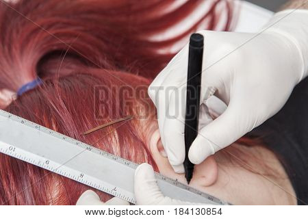 Professional marking the place for piercing on ear. Tragus type