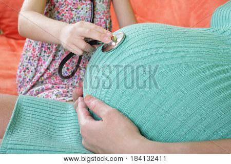 Daughter doctor using stethoscope white examining pregnant mother.