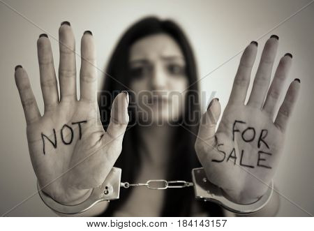 Woman in handcuffs on light background
