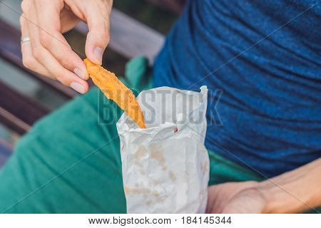 Man Eat Fried Sweet Potatoes In The Park. Junk Food Concept