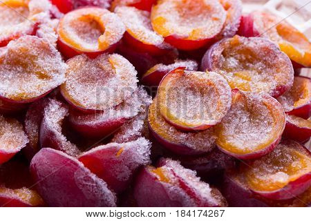 frozen half of a plum on a wooden background. Winter vitamins