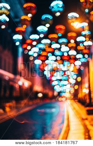 Defocused background of empty night city street with multiple bokeh circles of different colors beautiful colorful vertical view of blurred night lights on top during festival or celebration