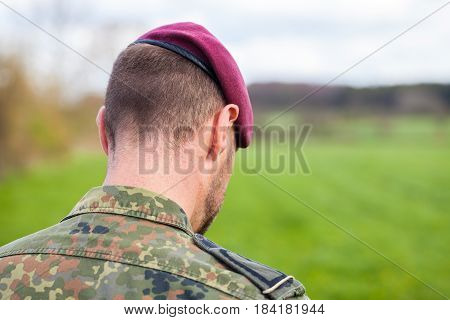 german soldier with a beret stands on a field background