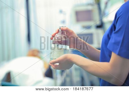 Transparent bottle in the hands of a nurse against the backdrop of a hospital ward