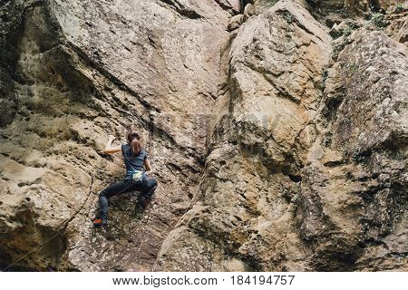 Sporty young woman free climbing on rock outdoor.