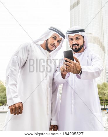 Arabic businessmen in Dubai watching smartphone outdoors