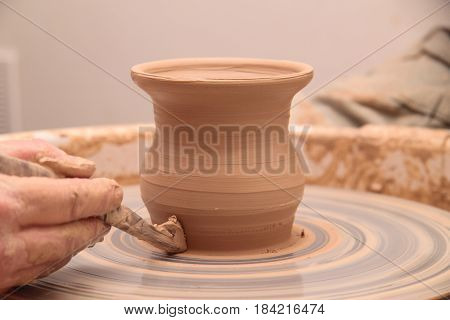 hands of a potter, creating an earthen jar on a pottery wheel