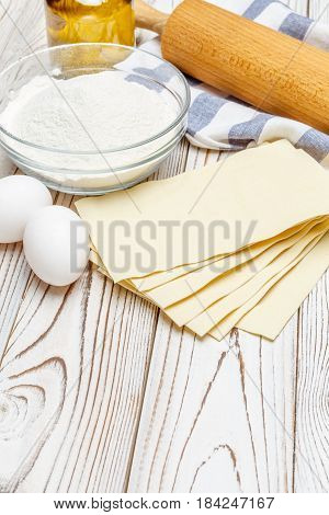 dried uncooked lasagna pasta sheets and ingridients on wooden table