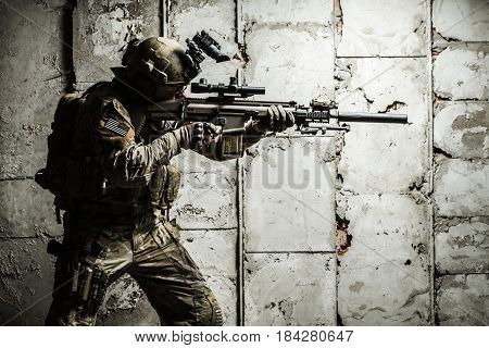 Army Ranger moving along the concrete wall on mission