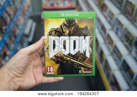Bratislava, Slovakia, circa april 2017: Man holding Doom videogame on Microsoft XBOX One console in store