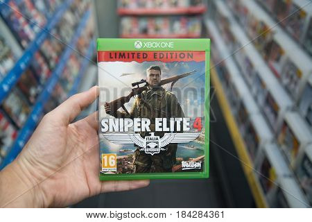 Bratislava, Slovakia, circa april 2017: Man holding Sniper Elite 4 videogame on Microsoft XBOX One console in store