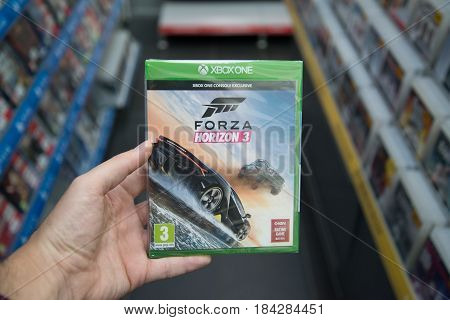 Bratislava, Slovakia, circa april 2017: Man holding Forza Horizon 3 videogame on Microsoft XBOX One console in store