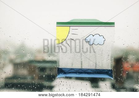water cycle in a bag. a  plastic bag with water and painted on it with a cloud and the sun hanging in the window. clouds form and rain fall in the bag. science experiment for children