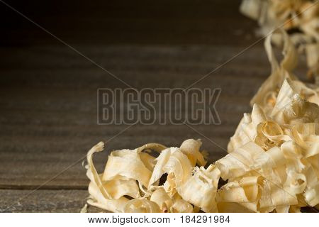 Light brown wood shavings from carpenter's hand planer or chisel work on wooden boards background with copy space