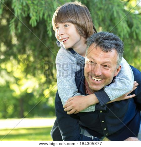 Portrait of father with his son having fun in summer park. Piggyback. Family fun. Happy boy playing with dad summer nature outdoor